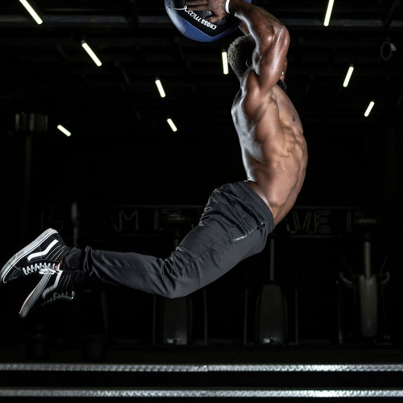 Man performing a controlled strength exercise in a dark gym.